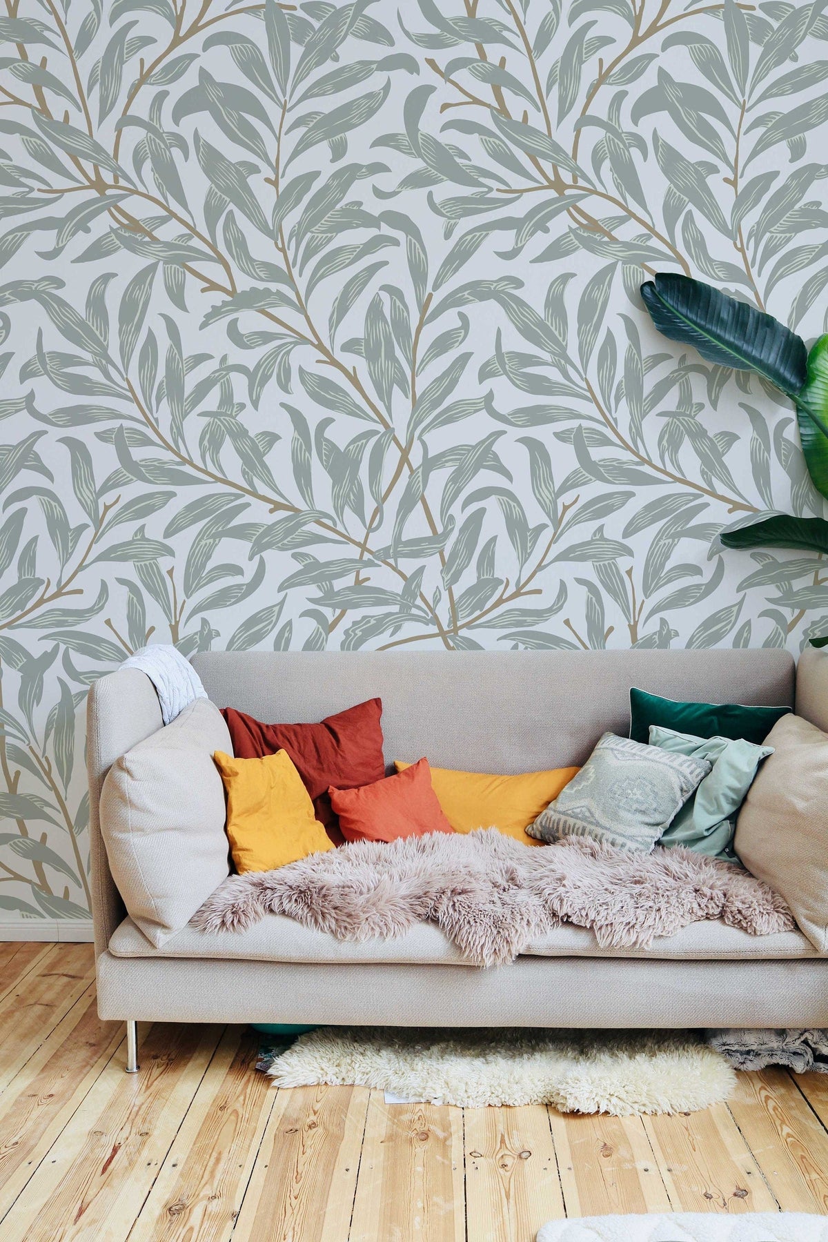 Willow Bough William Morris wallpaper on a living room wall behind a grey sofa