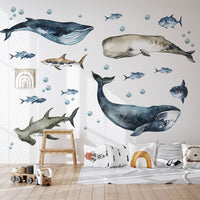 Wall with whale and fish decals in a room with a bed and toys.