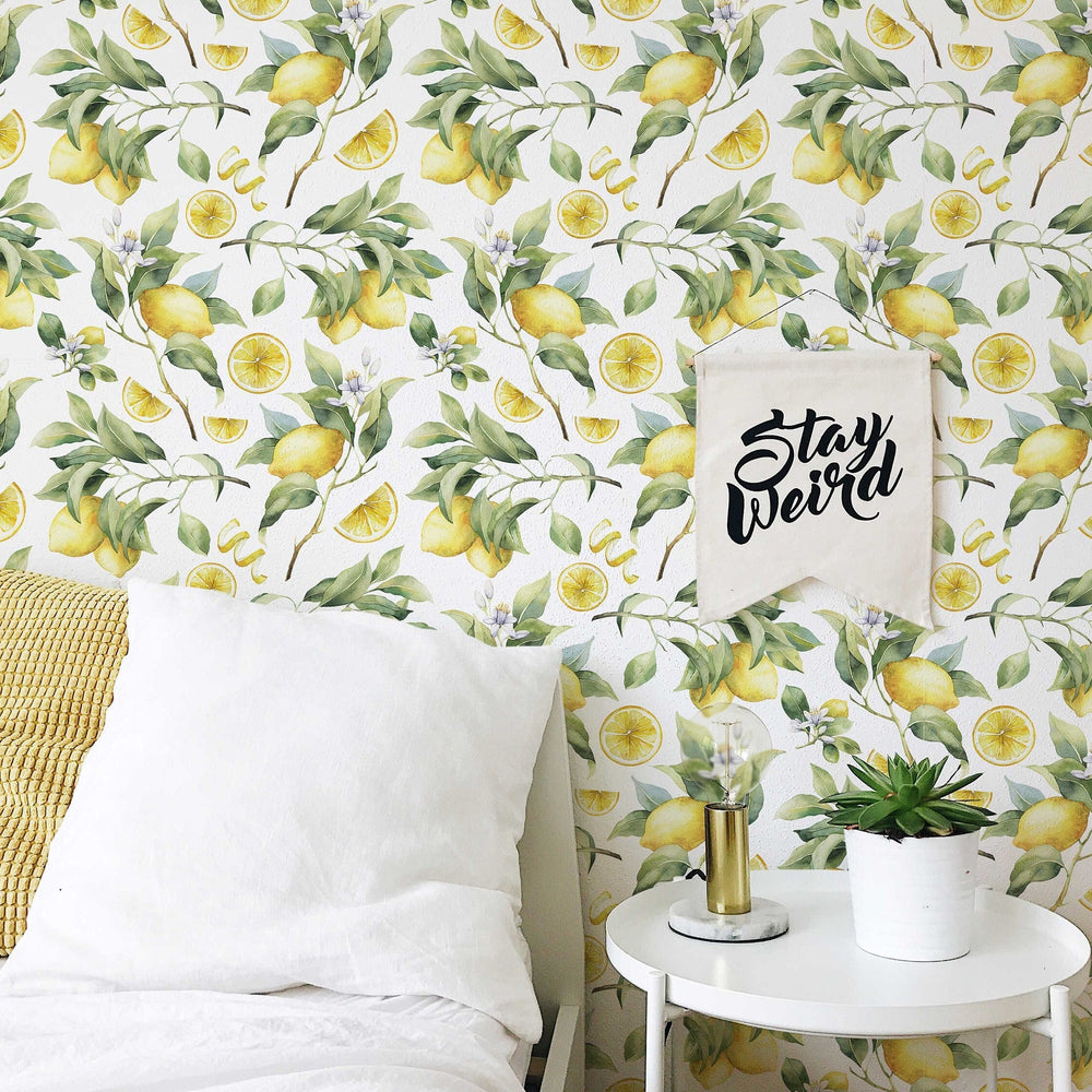 Watercolour lemon branches wallpaper behind a bed and side table