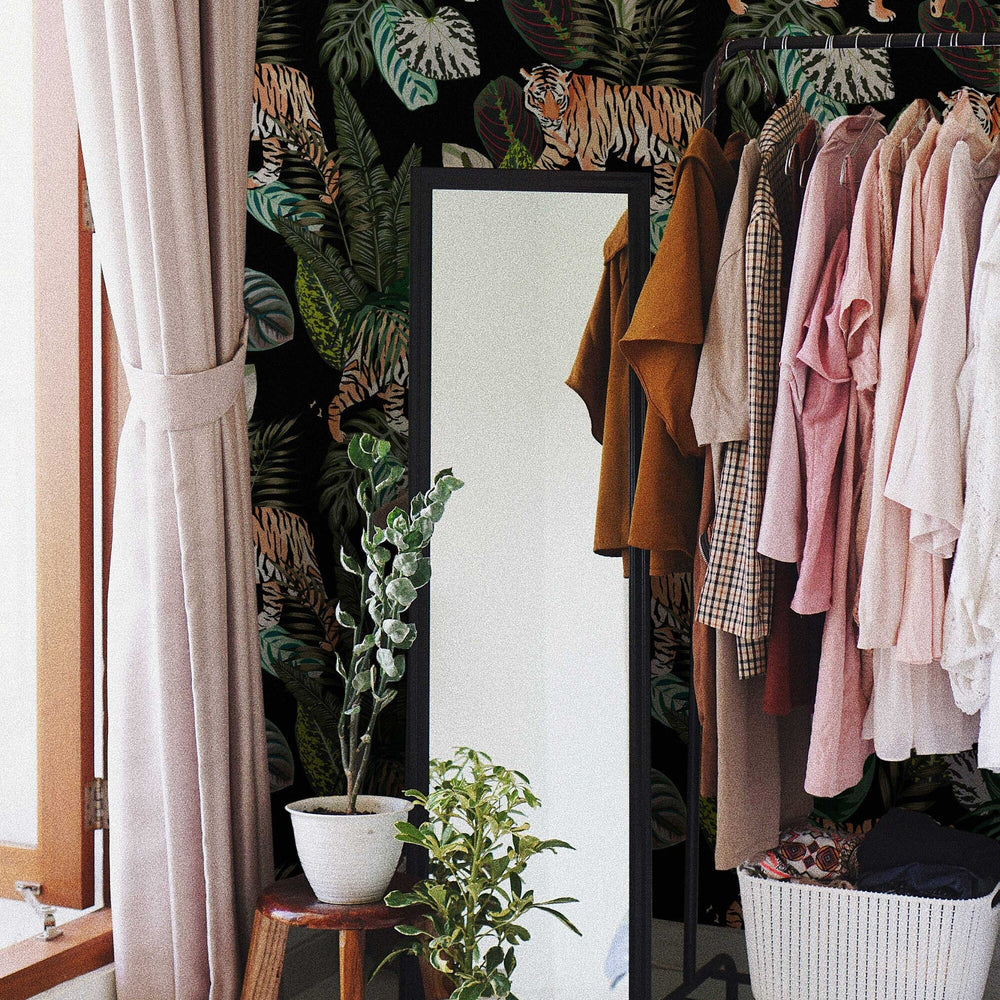 Dark tropical wallpaper with tigers among the leaves, behind a clothes rail and mirror