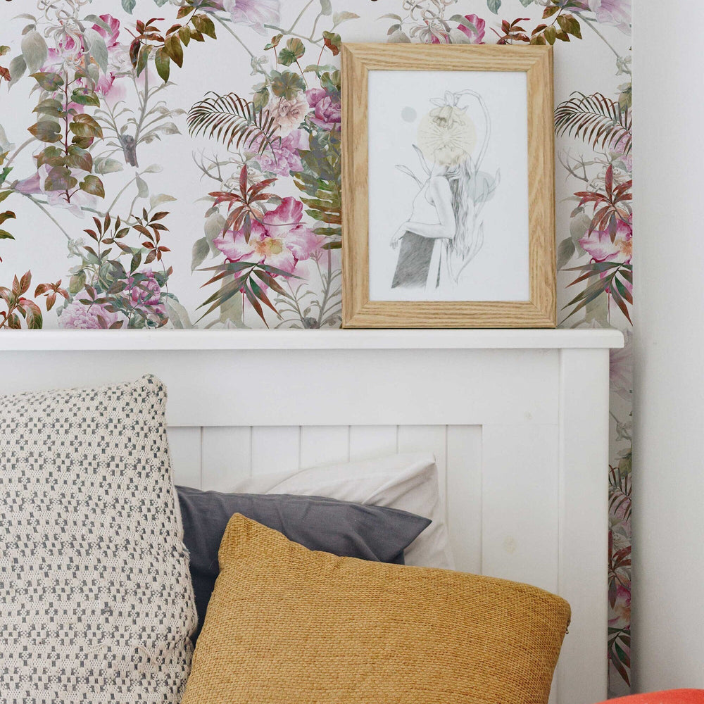 Pink tropical flowers and leaves wallpaper behind a bed with a framed sketch